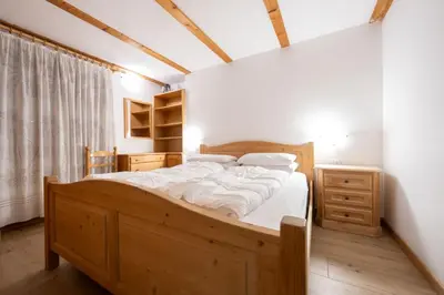 a bedroom with a large wooden bed with white sheets at Cesa alla Cascata in Canazei