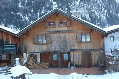 a large wooden house with snow on it at Cesa alla Cascata in Canazei