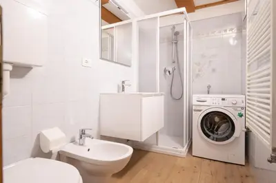 a bathroom with a toilet sink and a washing machine at Cesa alla Cascata in Canazei
