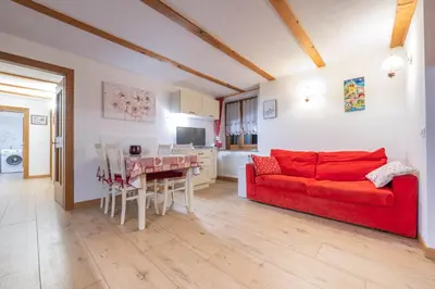 a living room with a red couch and a table at Cesa alla Cascata in Canazei