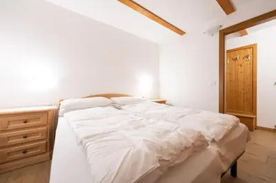 a large white bed in a room with a wooden dresser at Cesa alla Cascata in Canazei