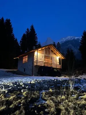 a log cabin in the snow at night at Chalet Pra Dell OSTIO Primiero San Martino di Castrozza in Fiera di Primiero