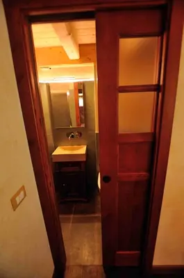 a bathroom with a sink and a wooden door at Chalet Pra Dell OSTIO Primiero San Martino di Castrozza in Fiera di Primiero