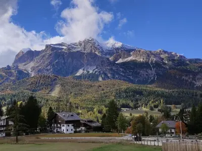 a mountain with a house in front of it at Appartamenti Codàn in San Vito di Cadore