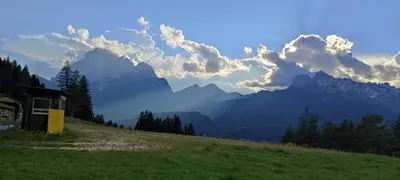 a house on a hill with mountains in the background at Appartamenti Codàn in San Vito di Cadore