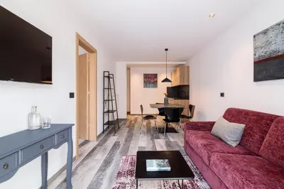 a living room with a red couch and a piano at Sole Boutique Hotel in Vipiteno