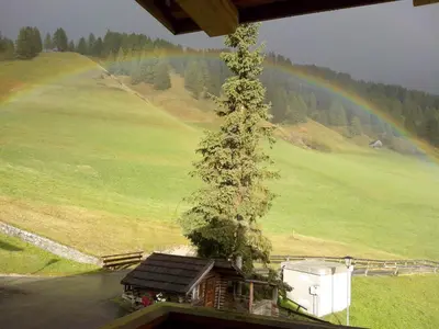 a tree on top of a house with a rainbow in the background at Villa Hilde in San Cassiano