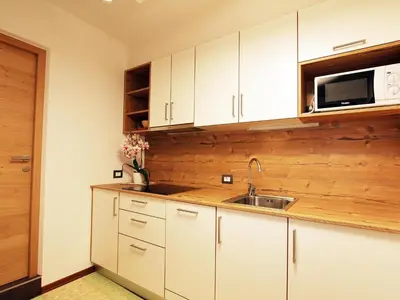 a kitchen with white cabinets and a sink and a microwave at Villa Hilde in San Cassiano