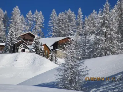a house covered in snow in front of trees at Villa Hilde in San Cassiano
