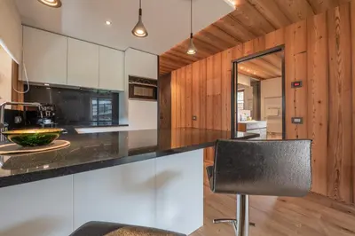 a kitchen with white cabinets and a black counter top at Mountainlodge Luxalpine in San Vigilio Di Marebbe