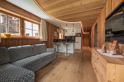 a living room with a couch and a kitchen at Mountainlodge Luxalpine in San Vigilio Di Marebbe