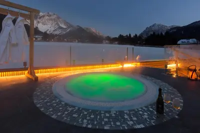 a hot tub with green water on a patio at Mountainlodge Luxalpine in San Vigilio Di Marebbe