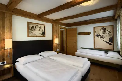 two beds in a room with wooden ceilings at Residence Ciasa Morin in Corvara in Badia