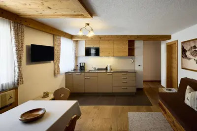 a kitchen and living room with a couch and a table at Residence Ciasa Morin in Corvara in Badia