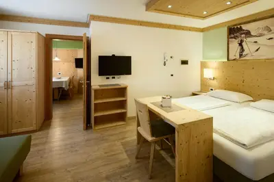 a bedroom with a bed and a desk and a television at Residence Ciasa Morin in Corvara in Badia