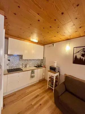 a kitchen with wooden ceilings and a couch in a room at Pragma Apartments - Appartamento Arcade in Predazzo