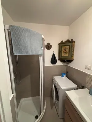 a small bathroom with a shower and a washing machine at Pragma Apartments - Appartamento Arcade in Predazzo
