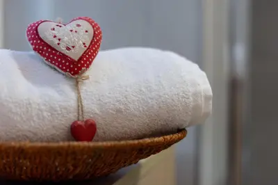 a basket filled with towels with a heart on it at DolomiApartments - Appartamento Avisio in Predazzo