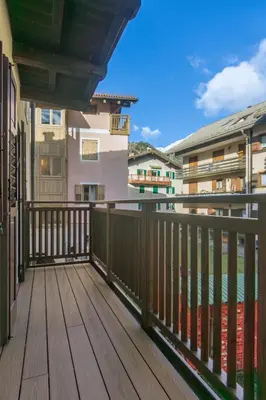 a balcony with a wooden deck and buildings at DolomiApartments - Appartamento Avisio in Predazzo