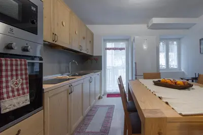a kitchen with a table with a bowl of fruit on it at DolomiApartments - Appartamento Avisio in Predazzo