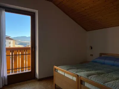 a bedroom with a bed and a balcony with a view at Casetta Turati in Castelfondo
