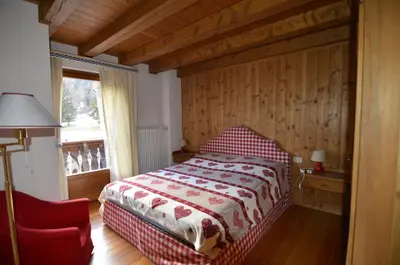 a bedroom with a bed and a red chair at Holidays on Dolomites in Villanova