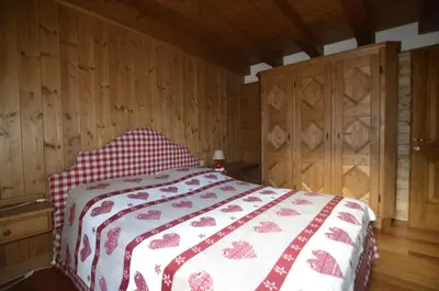 a bedroom with a bed with a red and white blanket at Holidays on Dolomites in Villanova