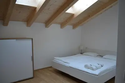a bedroom with a white bed and wooden ceilings at Gasthof Faust in Vols am Schlern