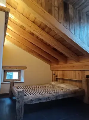 a bed in a room with a wooden ceiling at Brand new duplex in the Dolomites - Lupo Bianco in Rocca Pietore