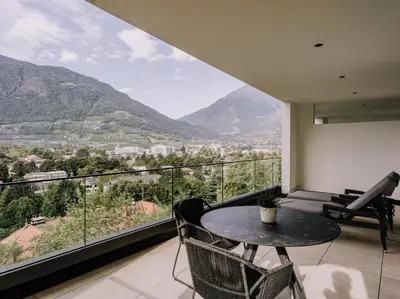 a balcony with a table and chairs and mountains at The Hills Merano in Merano