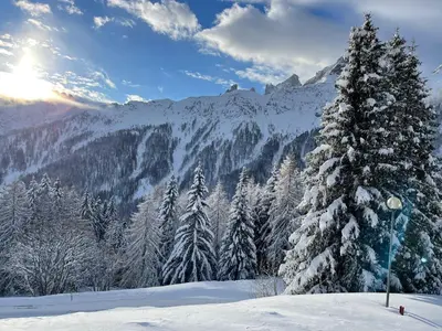 a snow covered mountain with the sun in the background at Casa Pisolo - presso Sussy Residence in Falcade