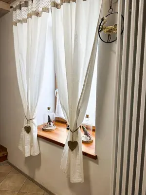 a window with white curtains on a window sill at B&B Piazza in Fondo