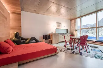a bedroom with a red bed and a table and chairs at Dichterstube im Living Kampill in Bolzano