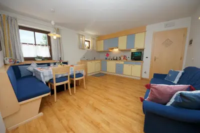 a living room with a blue couch and a kitchen at Apartments Nevada in Colfosco