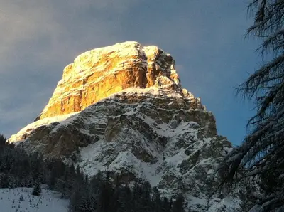 a mountain covered in snow with the sun shining on it at Apartments Nevada in Colfosco