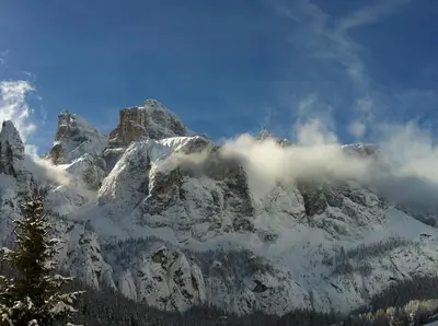 a mountain covered in snow and clouds in the sky at Apartments Nevada in Colfosco