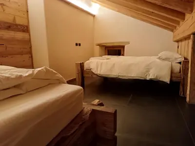 a room with two beds in a room with wood at Brand new Duplex in the Dolomites - Picchio Rosso in Rocca Pietore