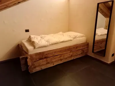 a small bedroom with a bed and a mirror at Brand new Duplex in the Dolomites - Picchio Rosso in Rocca Pietore