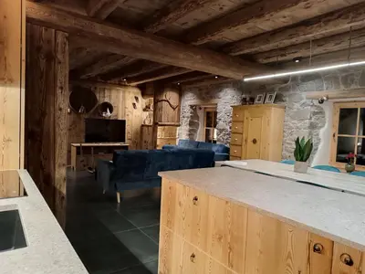 a kitchen and living room with wooden ceilings and blue furniture at Brand new Duplex in the Dolomites - Picchio Rosso in Rocca Pietore