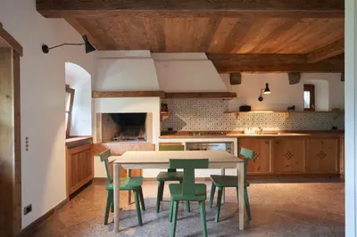 a kitchen with a table and green chairs at Beautiful barn with garden and stunning view in Colle Santa Lucia