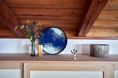 a table with a vase of flowers and a mirror at Beautiful barn with garden and stunning view in Colle Santa Lucia