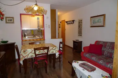 a living room with a table and a couch at Dolomitissime Holiday Homes Marmolada in Rocca Pietore