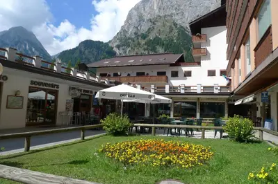 a building with a table and an umbrella in the grass at Dolomitissime Holiday Homes Marmolada in Rocca Pietore