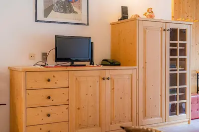 a wooden cabinet with a television on top of it at Dolomitissime Holiday Homes Marmolada in Rocca Pietore