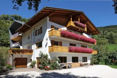 a large white building with flowers on the balconies at Haus Gabi Runggaldier in San Pietro in Gardena