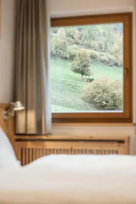 a bedroom window with a view of a green field at Haus Gabi Runggaldier in San Pietro in Gardena