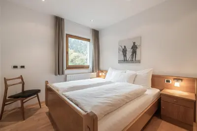 a bedroom with a bed with a chair and a window at Haus Gabi Runggaldier in San Pietro in Gardena