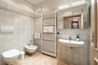 a white bathroom with a sink and a toilet at Haus Gabi Runggaldier in San Pietro in Gardena