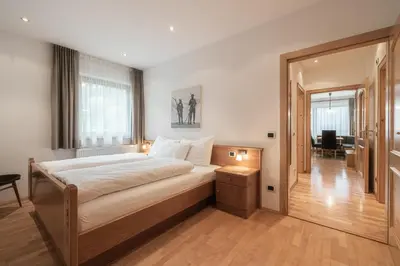 a bedroom with a large bed and a living room at Haus Gabi Runggaldier in San Pietro in Gardena