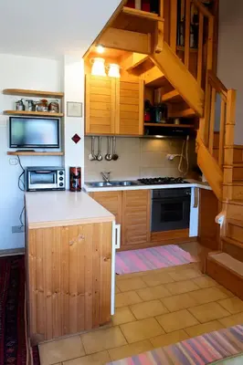 a kitchen with wooden cabinets and a staircase in a room at Appartamento Pepe by Sunhome Fiemme in Castello di Fiemme